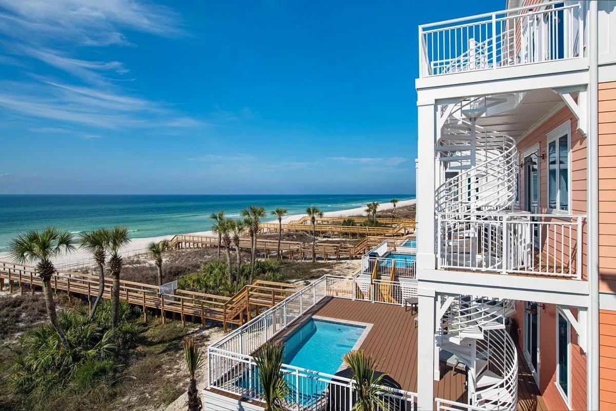 A serene private pool area with a wooden dune walkover leading straight to the sandy beach. The pool is surrounded by a spacious deck for sunbathing, and a spiral staircase connects the upper balcony to the outdoor oasis. Panoramic ocean views reinforce the villa’s beachfront luxury.